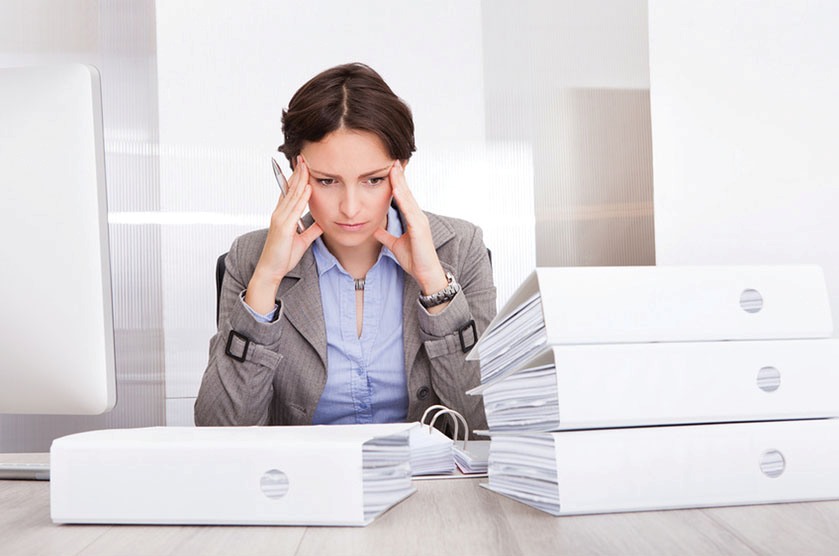 Portrait Of Stressed Businesswoman Looking At Stack Of Folders