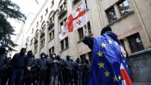 A protester waves a Georgian flag while wearing the European flag in front of policemen blocking a street during a rally against a draft bill on 'foreign agents' near the Parliament building in Tbilisi, Georgia, 14 May 2024. Georgian parliament deputies are set to adopt the law on 'foreign agents' at the plenary session on 14 May, in the third and final reading. Afterwards, the law will be sent to the Georgian president Salome Zourabichvili for signing, who has vowed to veto it. Fot. PAP/EPA/DAVID MDZINARISHVILI