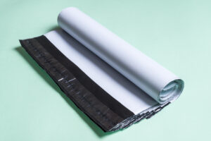 Białe foliopaki kurierskie ułożone na jasnozielonym tle