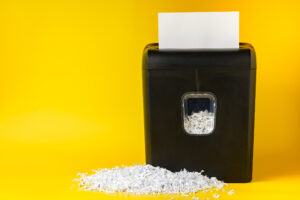 Office paper shredder on yellow studio background close up