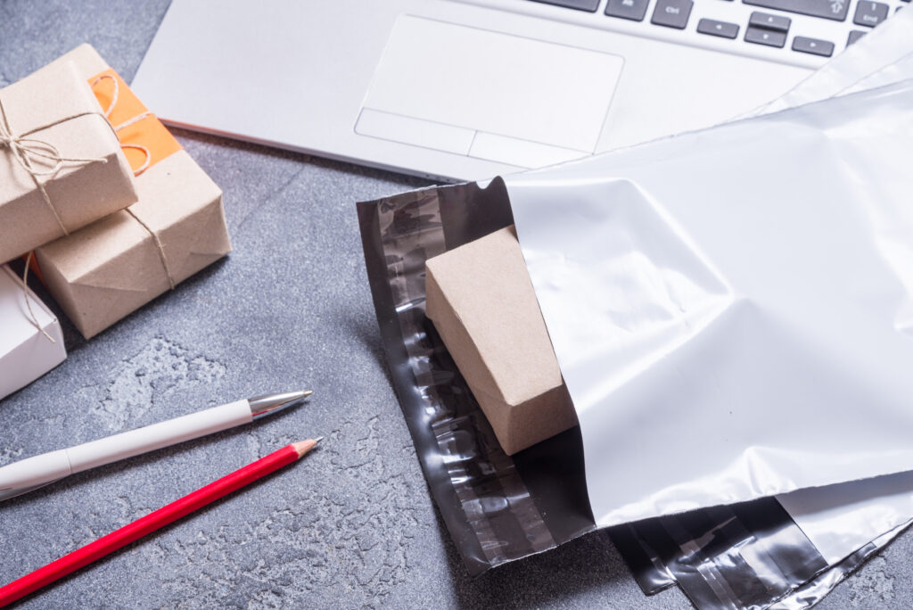 Otwarty foliopak kurierski na biurku z umieszczonym w środku pudełkiem