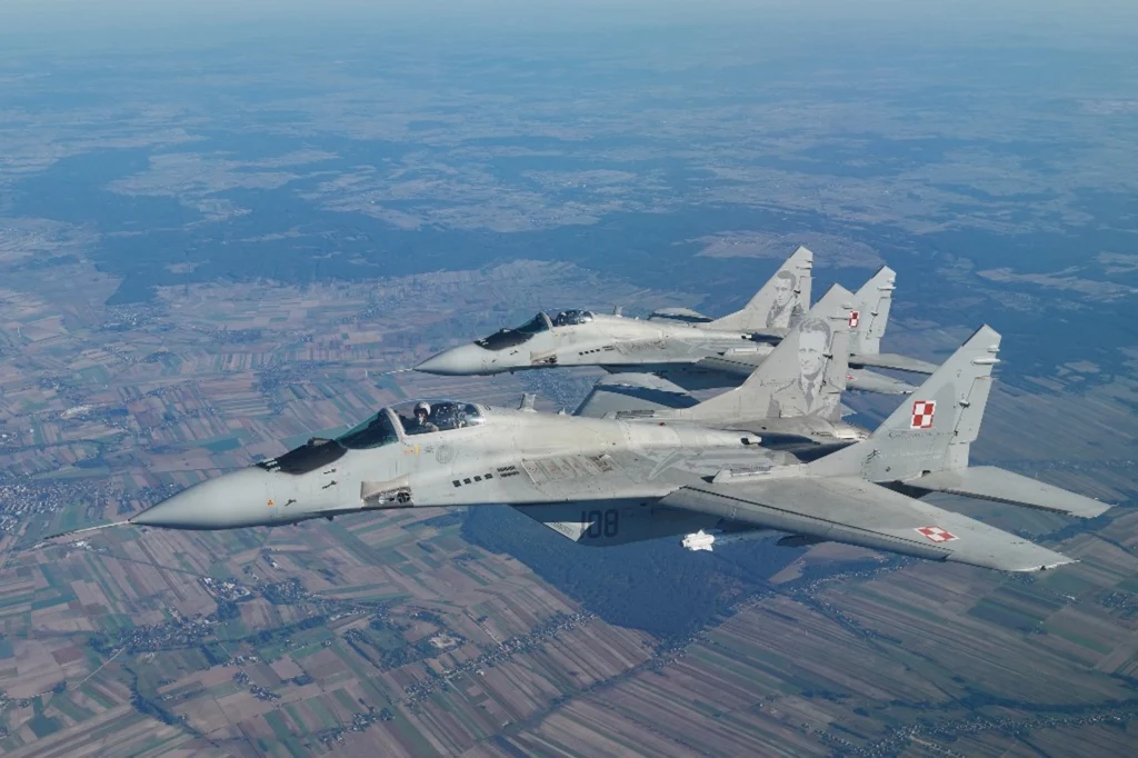 Dwa myśliwce MiG-29 biorą udział w ćwiczeniach osłony powietrznej NATO w pobliżu bazy lotniczej w Łasku, w centralnej Polsce, 12 października 2022 r. (Zdjęcie: RADOSŁAW JOŹWIAK / AFP)