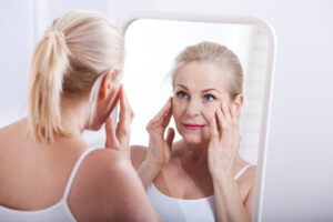 Middle aged woman looking at wrinkles in mirror. Plastic surgery and collagen injections. Makeup. Macro face. Selective focus on the face. Realistic images with their own imperfections.