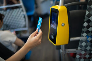 Asian woman hand paying conctactless with plastic card for the public transport in bus, tram or subway metro close up