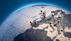 States and capitals of the European Union pinned with golden pins on a cork globe. The pins are connected to each other with a golden thread.