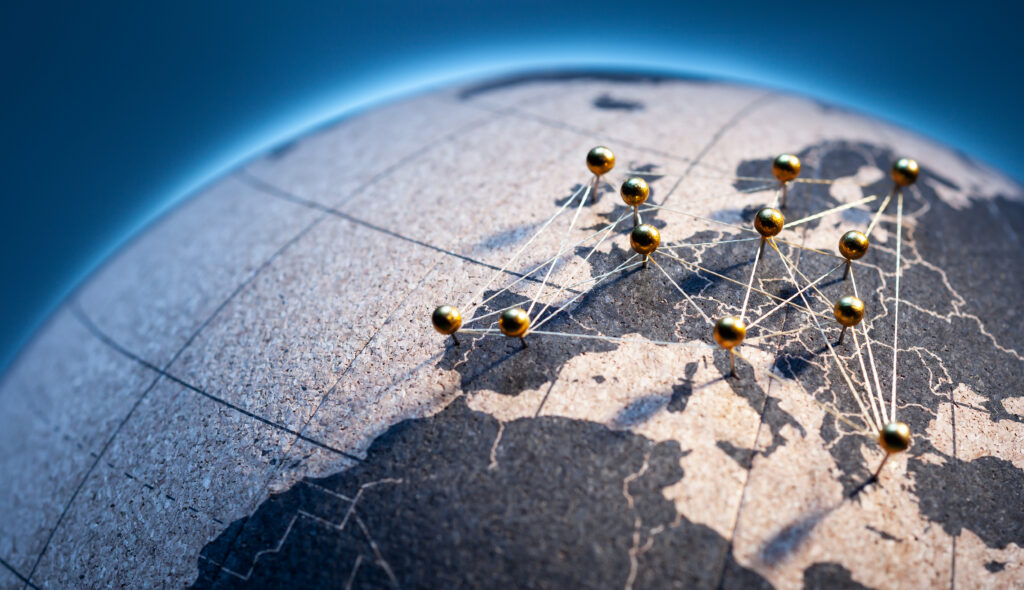 States and capitals of the European Union pinned with golden pins on a cork globe. The pins are connected to each other with a golden thread.